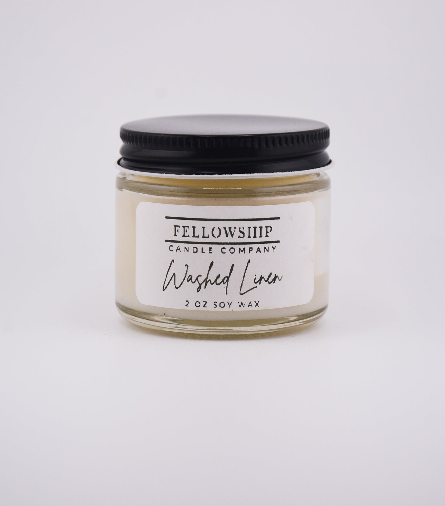 Candle jar labeled 'Washed Linen' by Fellowship Candle Company on a white background