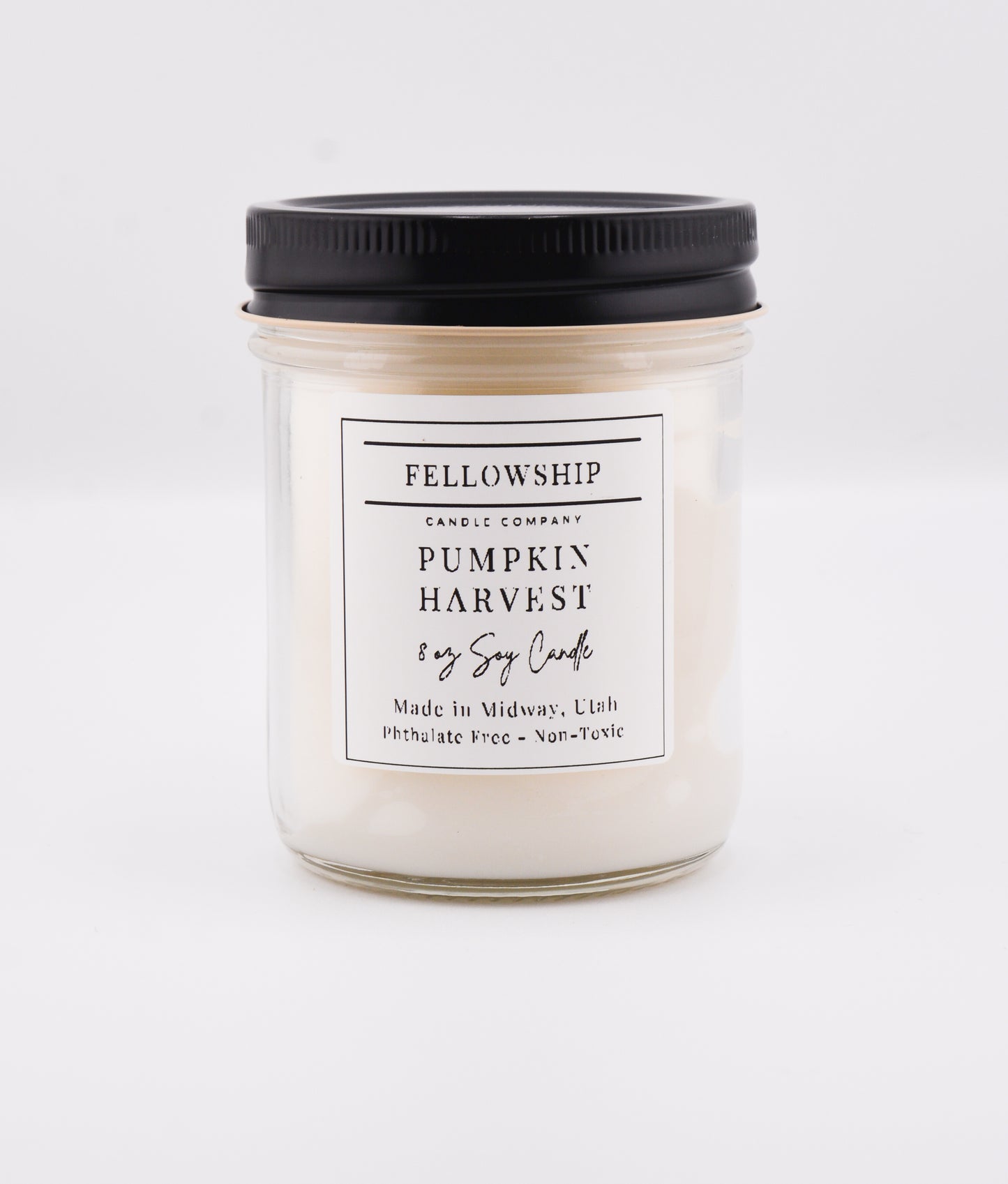 Candle jar labeled 'Pumpkin Harvest' from 'Fellowship Candle Company' on a white background