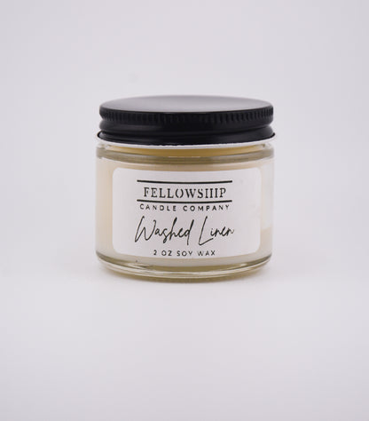 Candle jar labeled 'Washed Linen' by Fellowship Candle Company on a white background