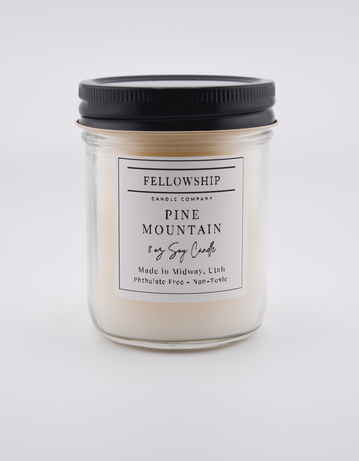 Jar candle labeled 'Pine Mountain' from Fellowship Candle Company on a white background