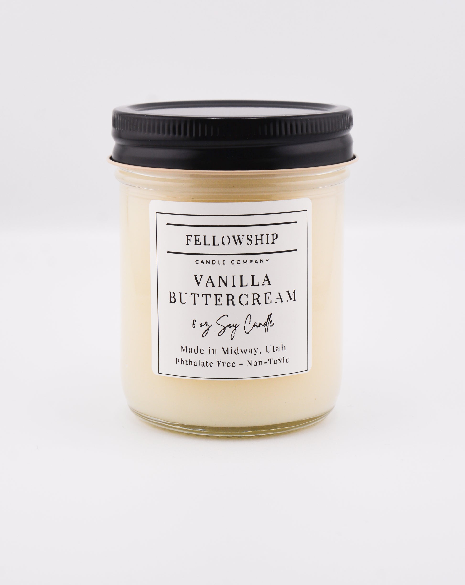 Vanilla buttercream candle with a black lid on a white background