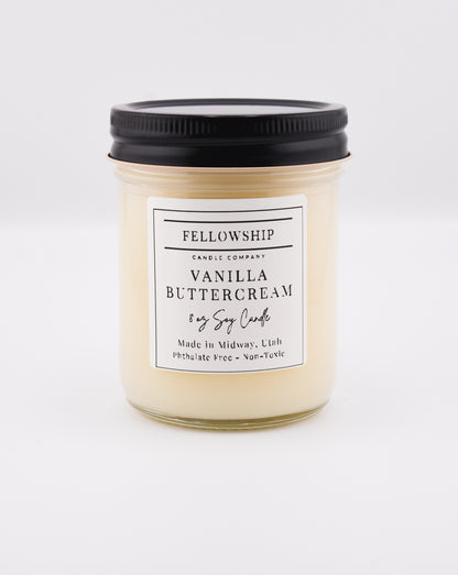 Vanilla buttercream candle with a black lid on a white background
