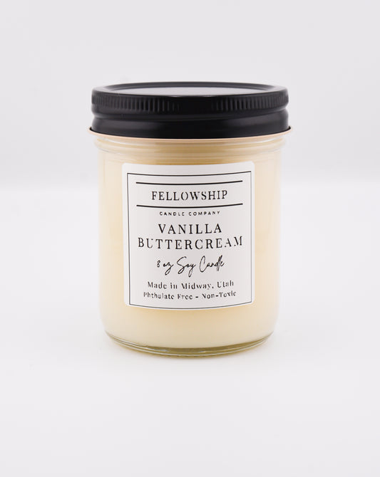 Vanilla buttercream candle with a black lid on a white background