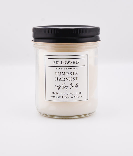 Candle jar labeled 'Pumpkin Harvest' from 'Fellowship Candle Company' on a white background
